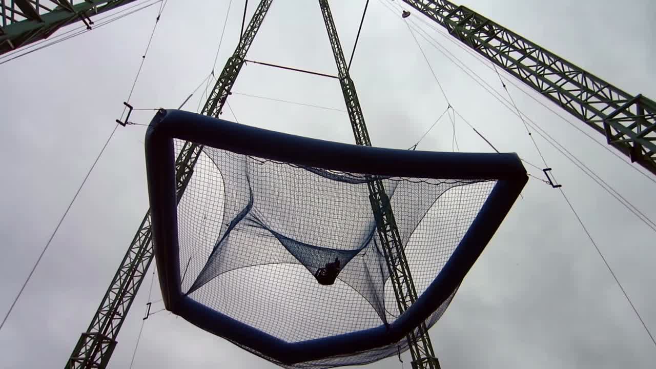 남자는 놀이 공원에서 거대한 매달린 트램폴린에 뛰어든다