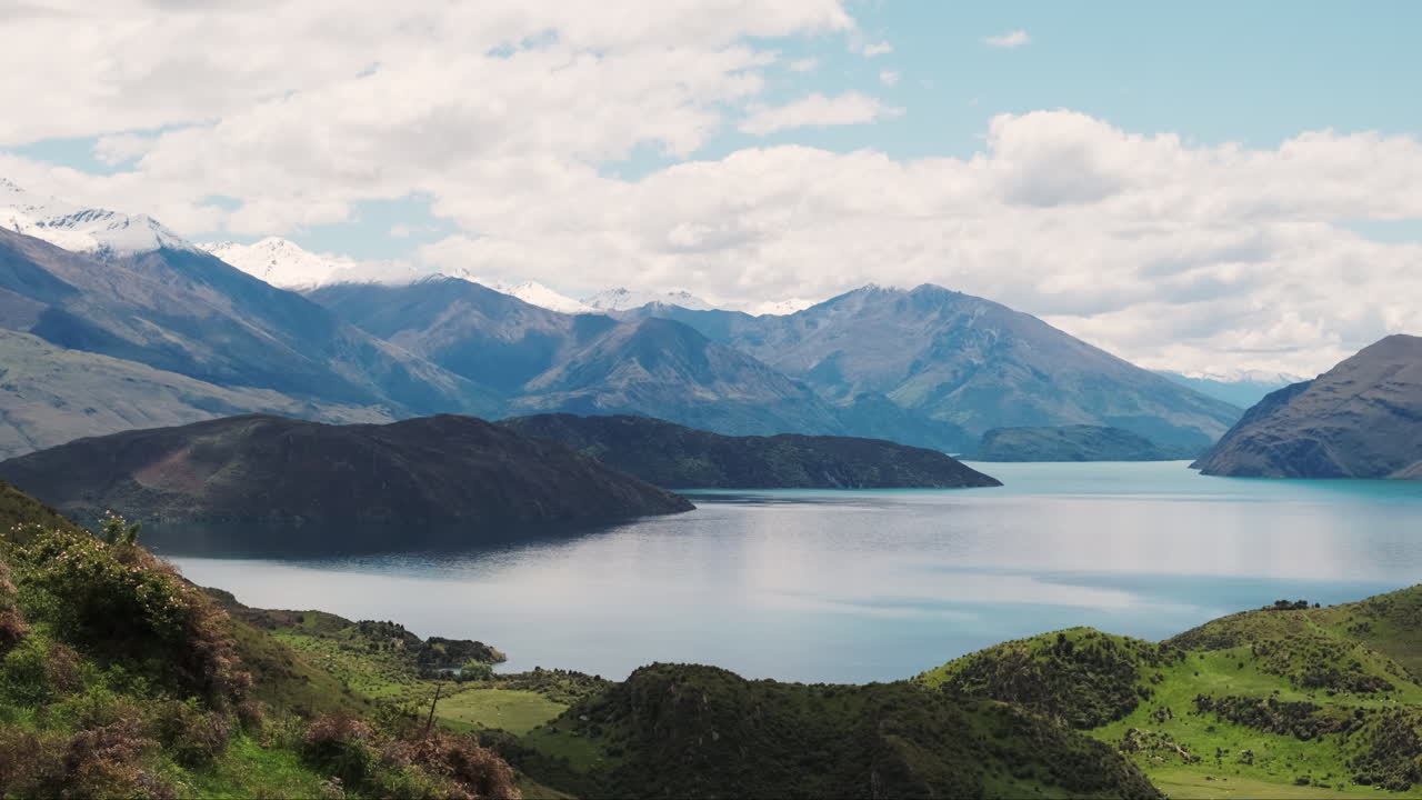 una cámara lenta sobre un impresionante paisaje de montaña y lago con un cielo parcialmente nublado
