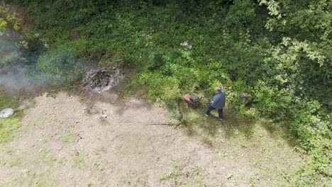 man using a weed wacker and clearing vegetation in a backyard