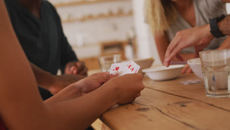 Mid-section-two-couples-at-a-table-playing-cards