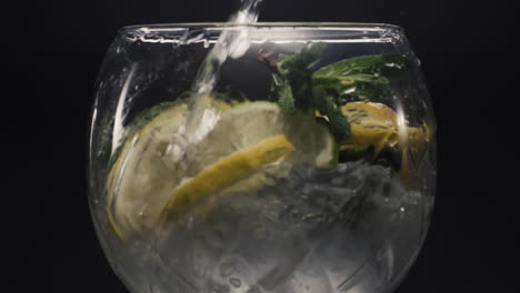 jet water filling lemon mint wineglass closeup. preparing homemade drink concept
