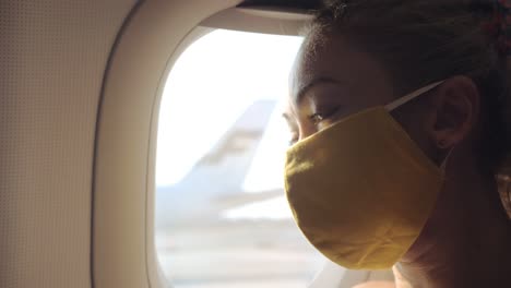 woman travel caucasian at plane with wearing protective medical mask. girl tourist at aircraft with protect respirator. coronavirus covid-19