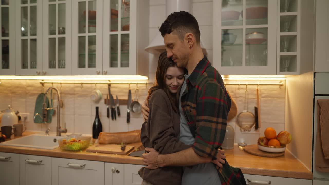 um casal a abraçar-se na cozinha.