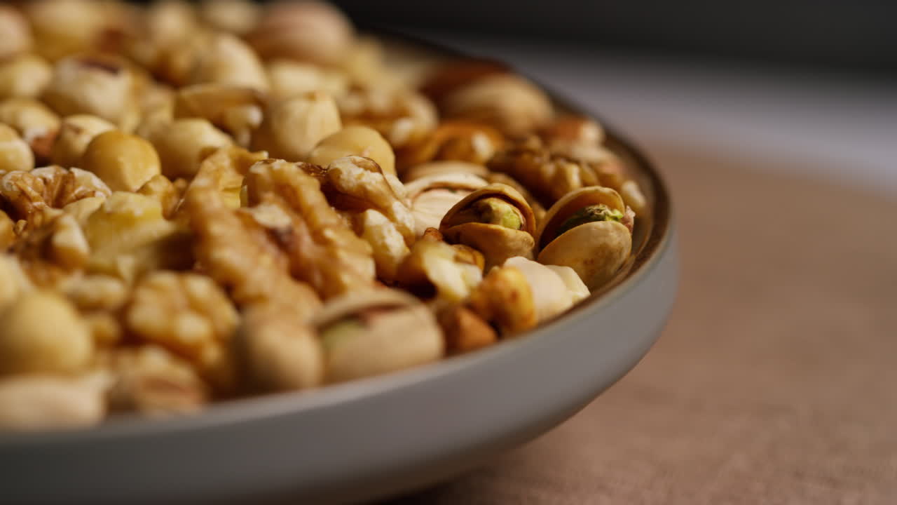Close Up Shot Of Rotating Bowl Containing Cashews Dry Roasted Peanuts Pistachio Walnuts And Hazelnut Nuts