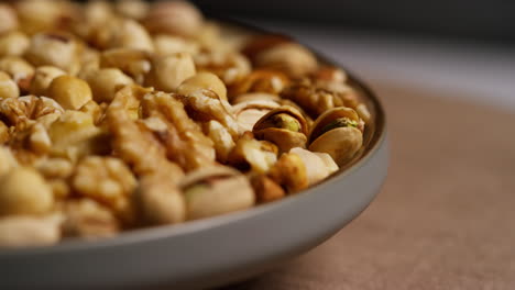 fotografía de cerca de un cuenco giratorio que contiene caju, cacahuetes tostados secos, pistachos, nueces y avellanas