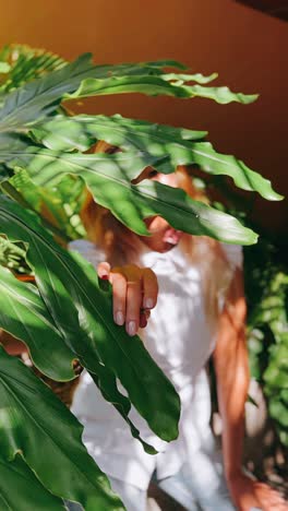 woman hiding behind tropical leaves