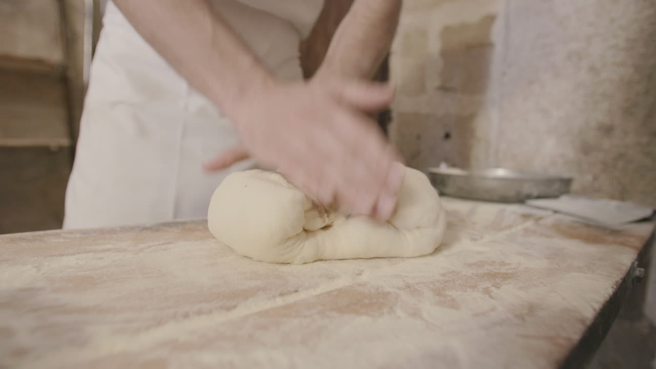 Riprese al rallentatore di un uomo che impasta e piega l'impasto della focaccia