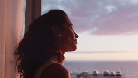 happy woman with arms raised enjoying early morning sunrise at home feeling peaceful freedom relaxing on vacation looking at beauiful ocean view