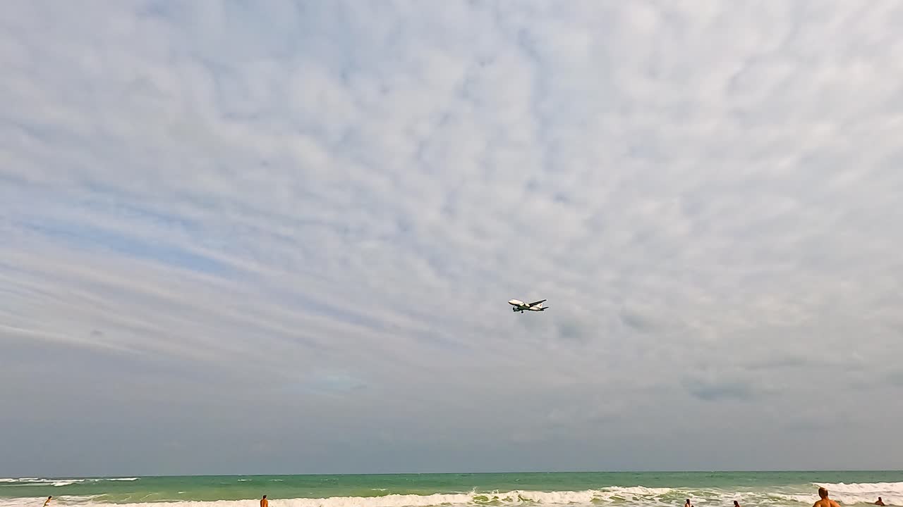 비행기가 해변에 접근하고, 사람들은 해변을 즐기고 있습니다.