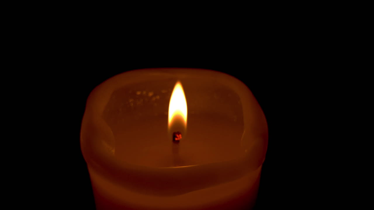 una sola llama en una vela, una mecha de vela encendida expuesta sobre un fondo negro