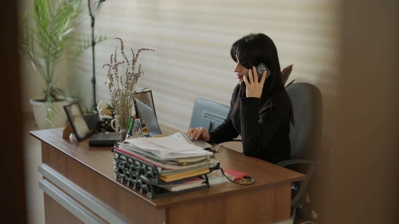 Donna professionista in un moderno ambiente d'ufficio, concentrata sul lavoro, vestita elegantemente in abiti da lavoro, circondata da attrezzature d'ufficio e un interno raffinato