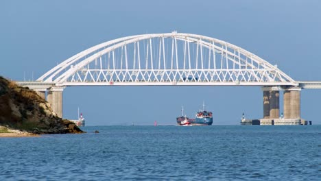 white arch bridge over waterway with ships