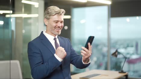 excited mature business man hold smartphone overjoyed businessman ceo executive winner celebrate mobile online bid game win victory success receive read good news