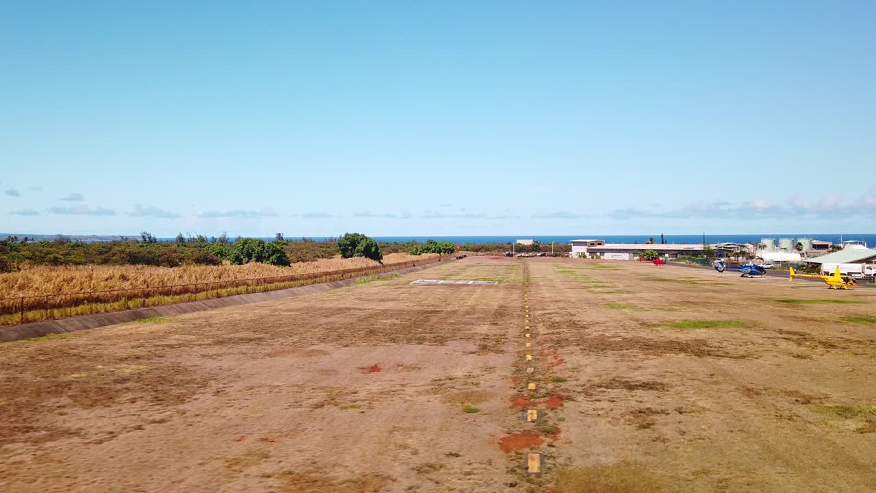 Gimbal wide shot from inside a door-less helicopter as it comes in for a landing at a heliport on the island of Kaua'i in Hawai'i