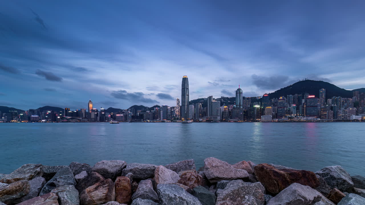 Day to night time lapse with clouds moving over Victoria Harbour Hong Kong skyline