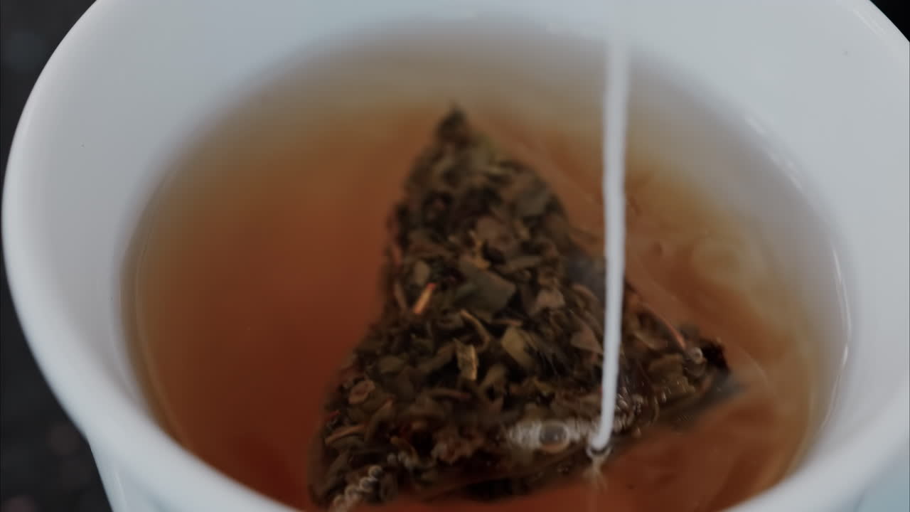 Close up of a green teabag in a white mug