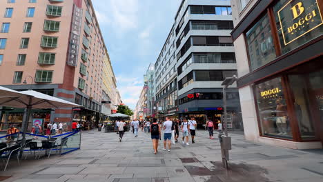 vienna, austria - june 9, 2025: explore vibrant shopping streets in wien. tourists stroll along bustling city streets in wien, austria, enjoying shops and cafes under a cloudy sky