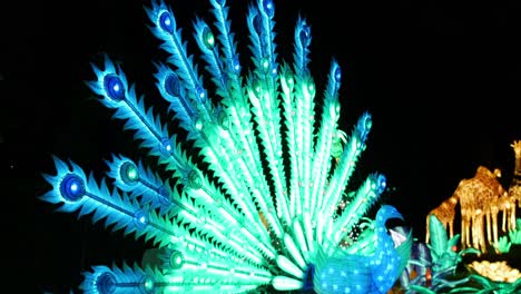 um ângulo de perfil de um pavão animatrônico iluminado enquanto abre suas penas revelando uma bela luz verde e azul