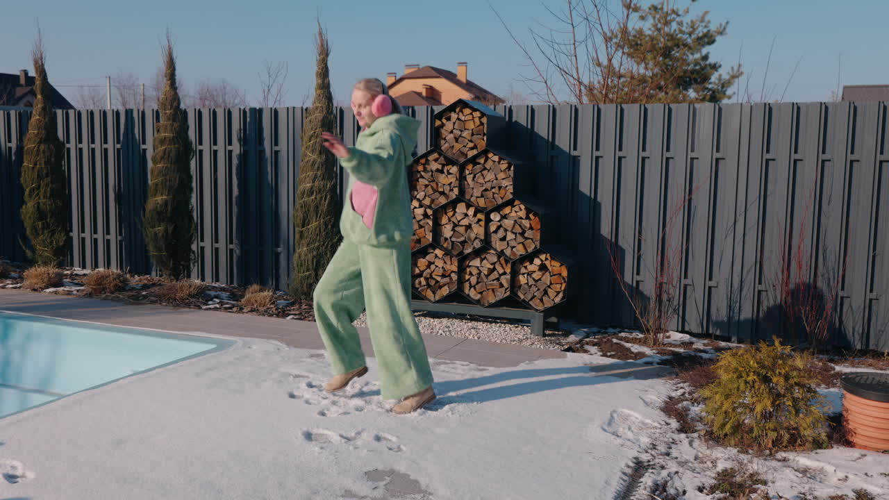 Donna che balla nella neve vicino alla piscina in inverno.