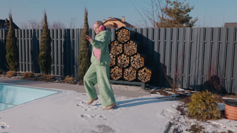 woman dancing in the snow by the pool in winter