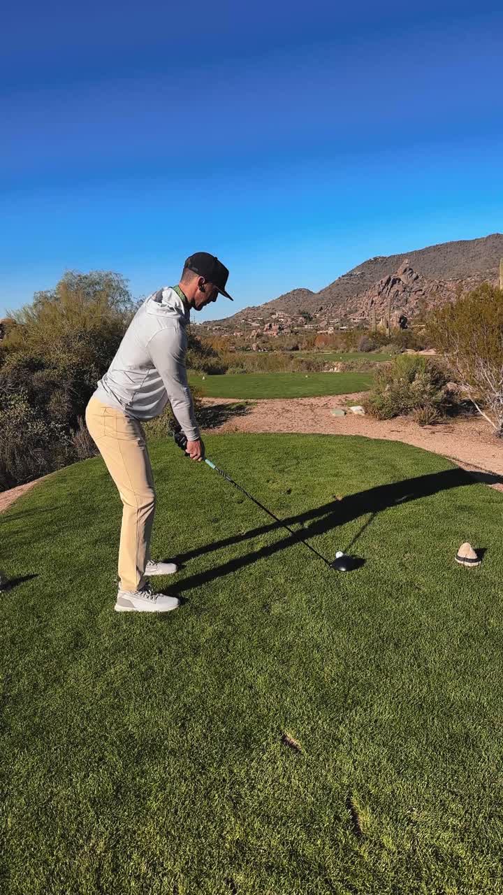 Golfista esegue il primo colpo dal tee in un bellissimo campo da golf nel deserto, ripresa verticale in una giornata di sole 4k con il driver