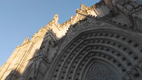 grand view of the gothic cathedral of barcelona with towering spires and intricate details, sunlight on top and shadow across archway