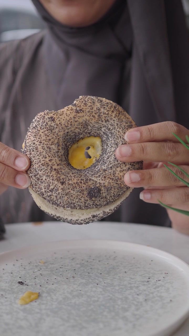 Person Holding a Poppy Seed Bagel with Cream Cheese