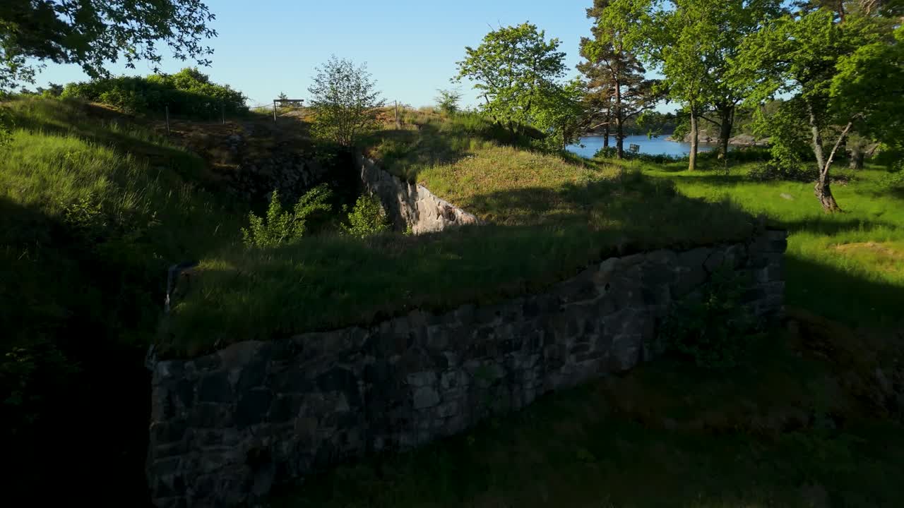 Rovine del Castello di Dalaborg, Mellerud, Svezia — sorvolo aereo, antiche mura in pietra, fortezza ricoperta di vegetazione, foresta lussureggiante, scorcio del Lago Vänern, estate.