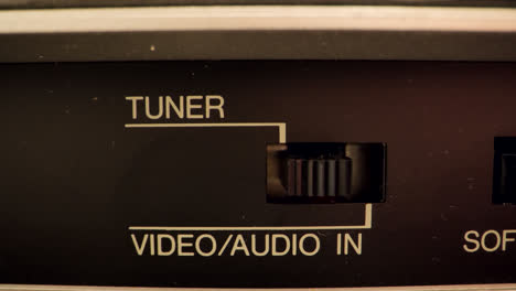 extreme close up of a button on a vintage vcr switching from video and audio in to a tuner