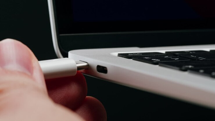 Hand plugging USB-C cable into laptop