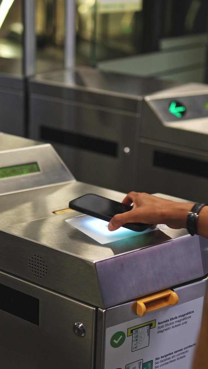 Mano che tocca lo smartphone per il pagamento senza contatto al tornello della metropolitana