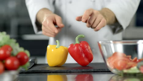 cerrar las manos del chef poniendo pimienta en cámara lenta en el restaurante de la cocina