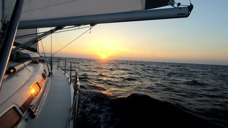 Eine-Yacht,-Die-In-Den-Sonnenuntergang-Segelt,-Mit-Wunderschönen-Farben,-Die-Die-Sonne-Widerspiegeln