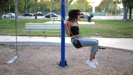 Ein-Wunderschönes-Hispanisches-Mädchen,-Das-Auf-Der-Schaukel-Auf-Dem-Spielplatz-Spielt-Und-Spaß-Hat,-Trägt-Eine-Retro-rosa-Sonnenbrille-In-Zeitlupe