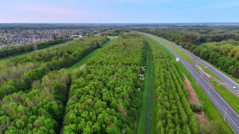 green landscape by highway, nl. aerial view of a vibrant green landscape beside a busy highway in the netherlands showcasing nature's beauty
