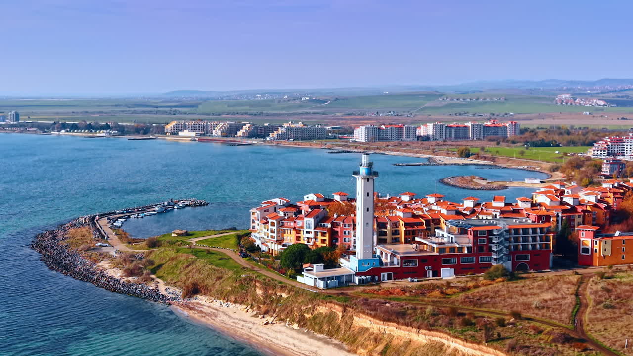 Beautiful residential neighborhood with a lighthouse at the coast of the sea. Lovely pier with some boats nearby. Bulgaria