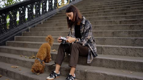 woman sitting on stairs with her dog and camera