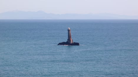 vista de alto ángulo del faro de la roca karori en el estrecho de cook con la isla sur en el fondo, costa sur de wellington, nueva zelanda