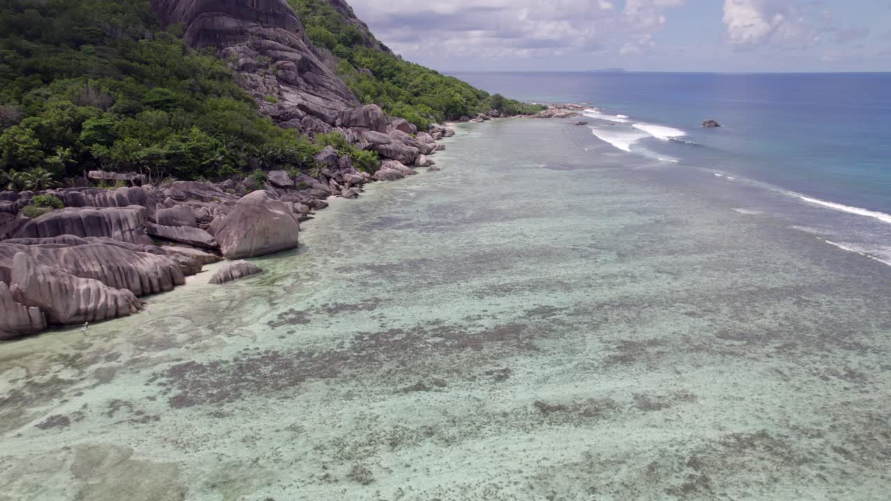 Plan drone en recul d'une spectaculaire plage à marée basse et des rochers de granit de l'Anse Source d'Argent, La Digue, Seychelles 005 30fps.