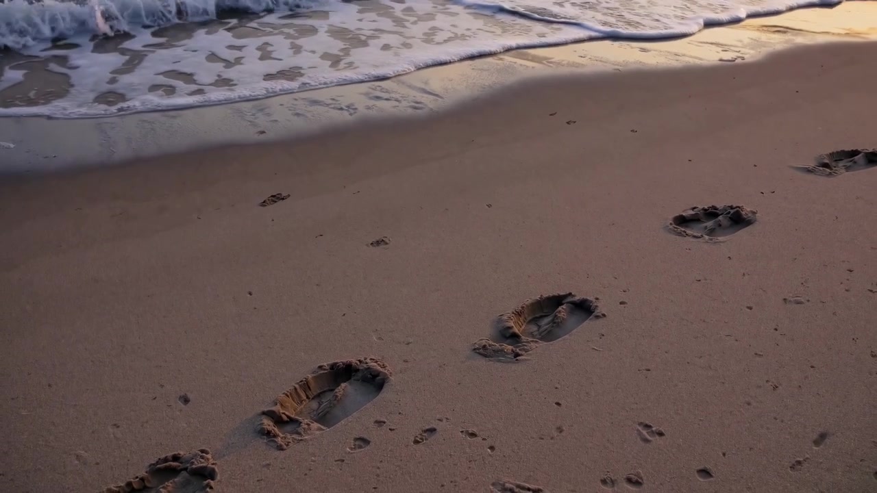 Impronte sulla sabbia di una spiaggia al tramonto