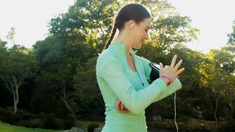 woman adjusting music settings on armband from smartphone