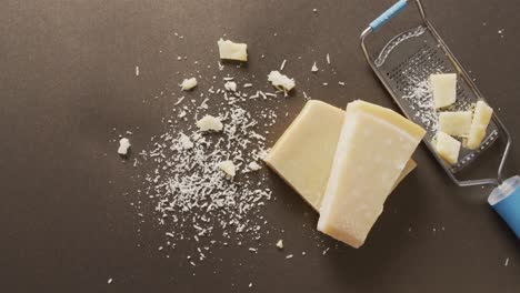 video of block of parmesan cheese and cheese grater cheese on wooden table