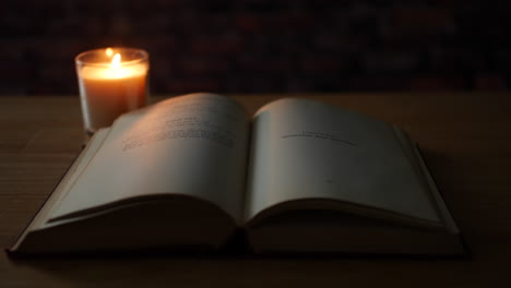 pages of an old antique book turning in the wind next to a candle in a dark room