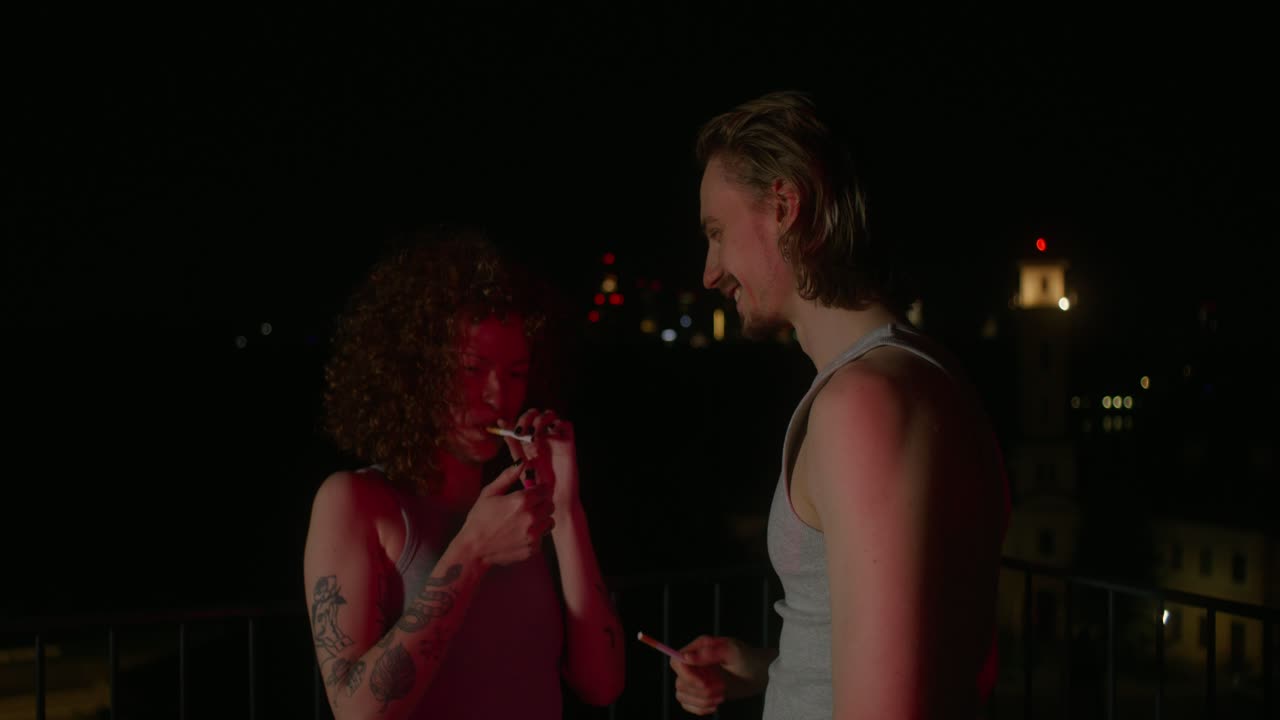Coppia che fuma su un tetto di notte