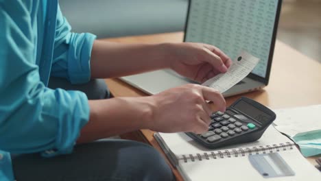 close up of man's hand holding bill and calculating money by calculator