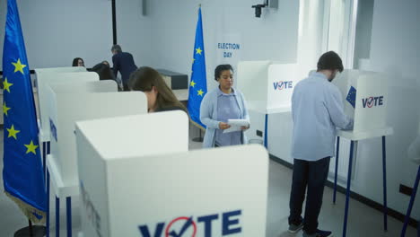 multiethnic european voters fill out ballots in voting booths high angle of multiethnic european people voting at polling station during eu elections diverse voters fill out ballots in voting booths election day in the european union civic duty and democracy