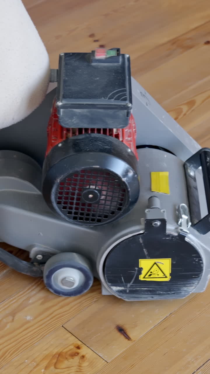 Hand of person turns on industrial sanding machine, vertical view