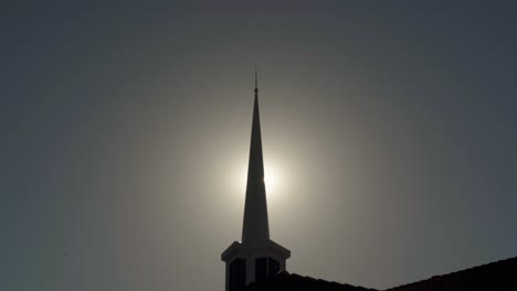 sun peeks through silhouetted mormon church spire