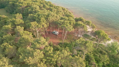 camper van in dense pine tree forest by the croatian shoreline