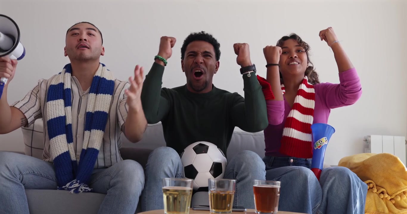 Grupo diverso de amigos animando un partido de fútbol en casa